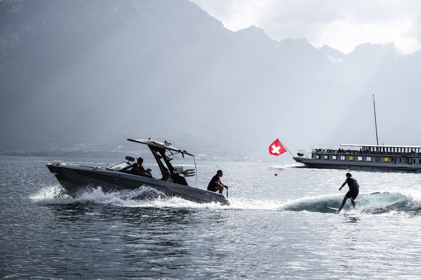 Bateau tractant un rider de wakesurf, drapeau suisse et bateau CGN en arrière-plan sur le lac Léman